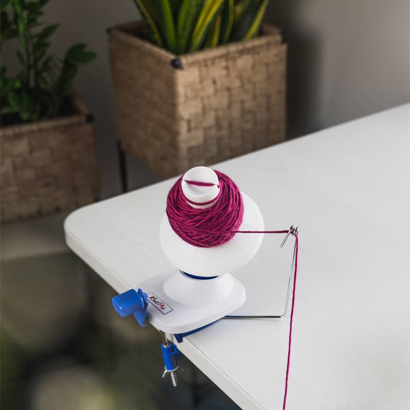 KnitPro Ball Winder clamped to a table while winding a centre-pull yarn cake